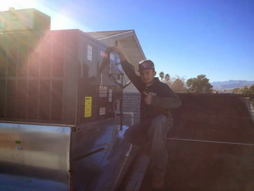 HVAC technician performing AC Tune-Up on a rooftop unit in Sandston